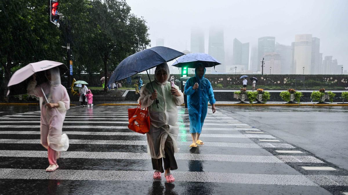 Warga Shanghai China di tengah cuaca buruk. (Hector RETAMAL/AFP)